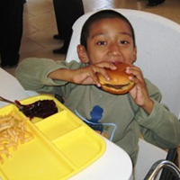 Small boy eating burger at cafeteria